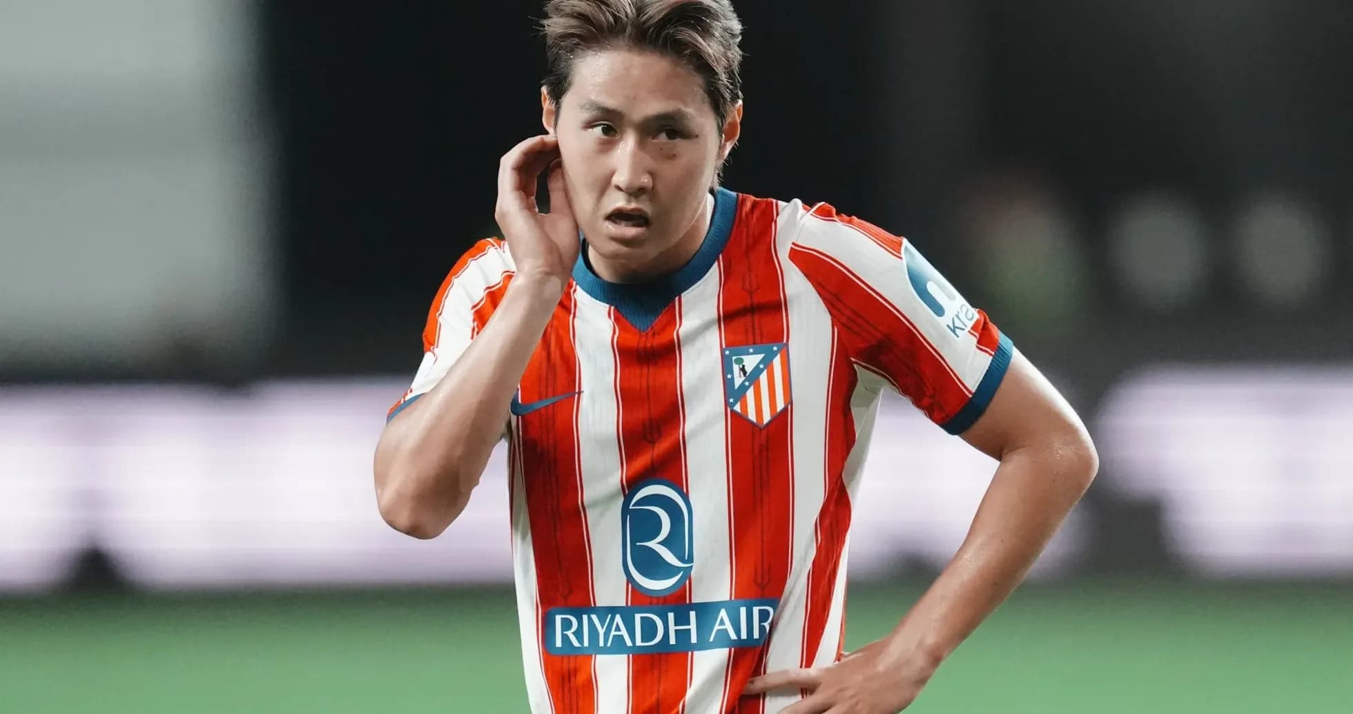 Futbolchi o'yin davomida qo'lini quloq tomon tutmoqda