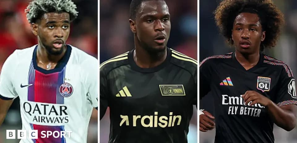 Three football players in team kits on the pitch