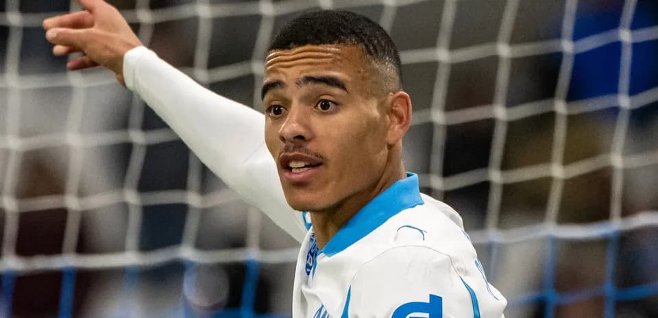 Futbolchi maydonda raqobatlashmoqda, to'pga ishora qilmoqda