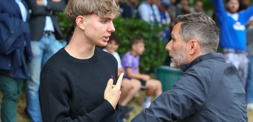Young man and adult discussing on sidelines