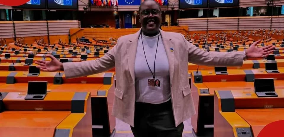 Woman standing in empty parliamentary chamber with arms open