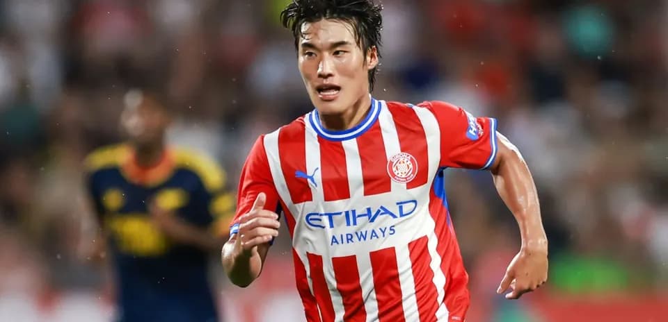 Futbolchi maydonda yugurayotgan qizil futbolka kiygan