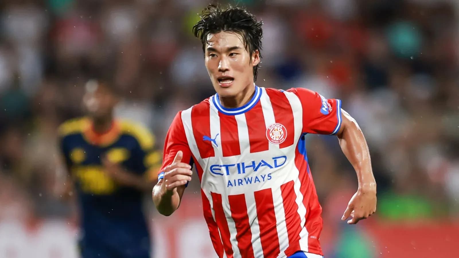 Futbolchi maydonda yugurayotgan qizil futbolka kiygan
