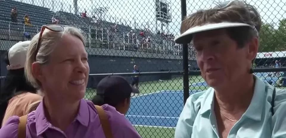 Two women talking at tennis match near court
