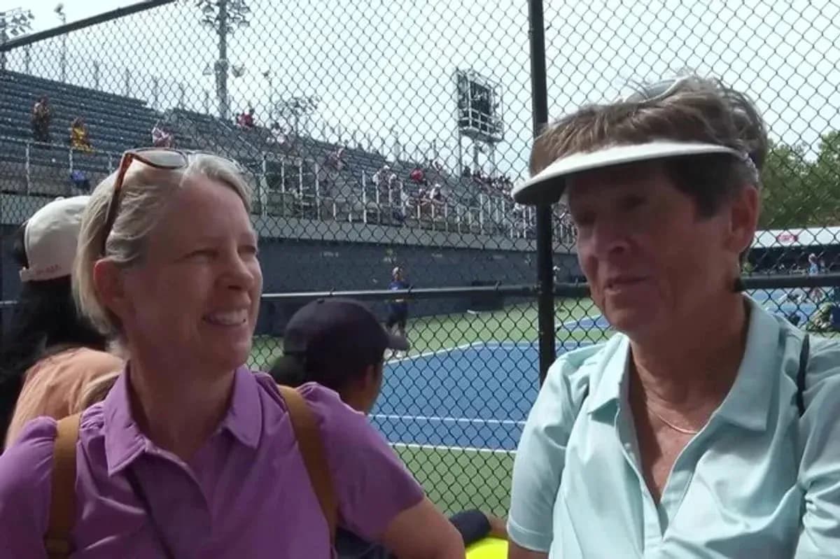 Two women talking at tennis match near court