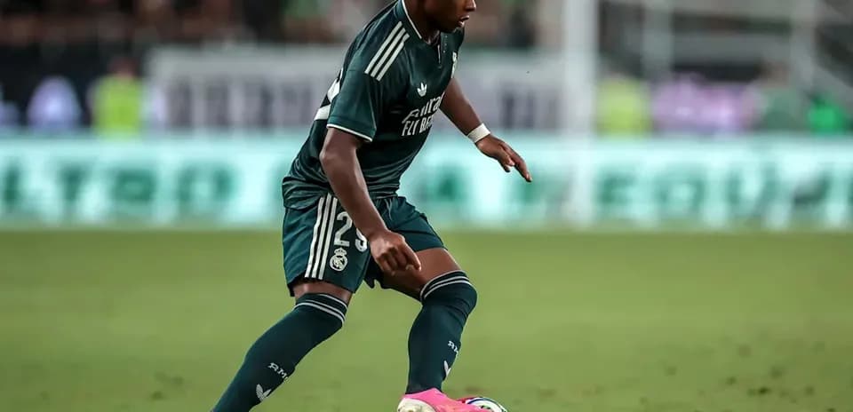 Futbolchi Real Madrid formasida to'p bilan harakatda