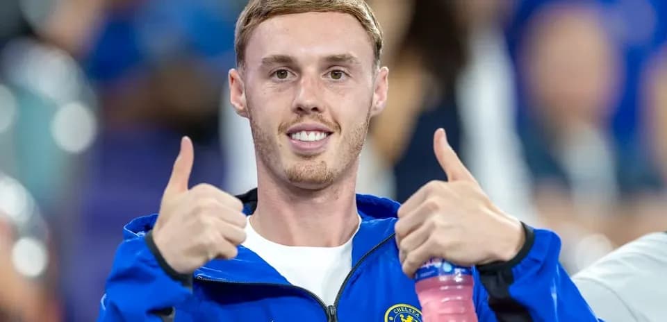 Futbolchi Chelsea formasida ikki barmoqni yuqoriga ko'taradi