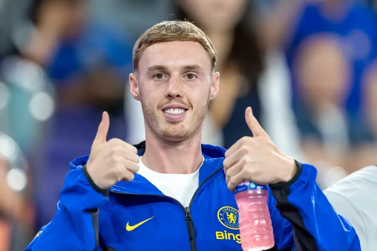 Futbolchi Chelsea formasida ikki barmoqni yuqoriga ko'taradi