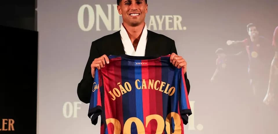 João Cancelo holding Barcelona jersey at presentation