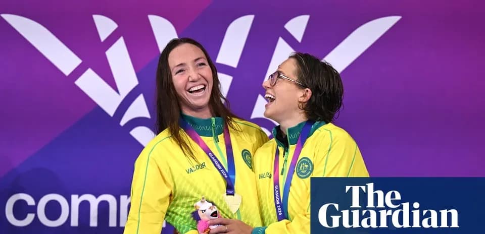 Ikki suzuvchi medal bilan sahnada tabassum qilmoqda