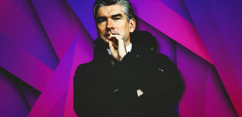 Man in coat with hand on chin against colorful background