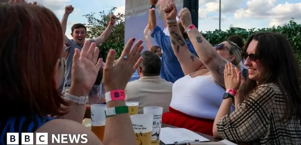 People celebrating with raised arms at outdoor venue
