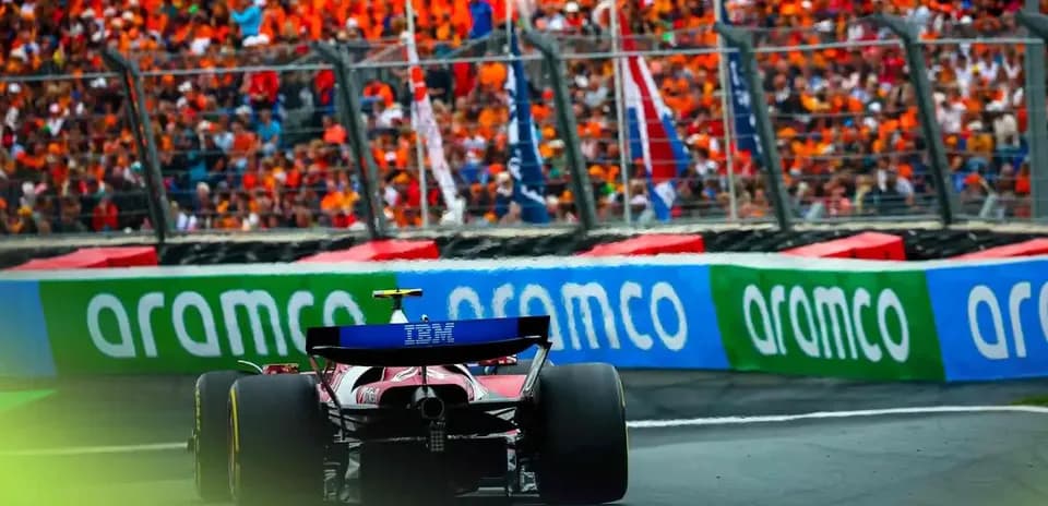 Formula 1 car racing past enthusiastic crowd