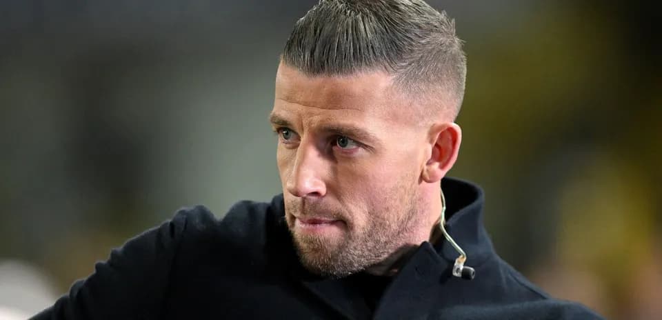 Yuzida ko'k palto kiygan futbolchi yaqin planda