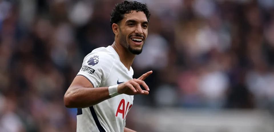 Futbolchi maydonda qo'lini ko'tarib raqibga murojaat qilmoqda