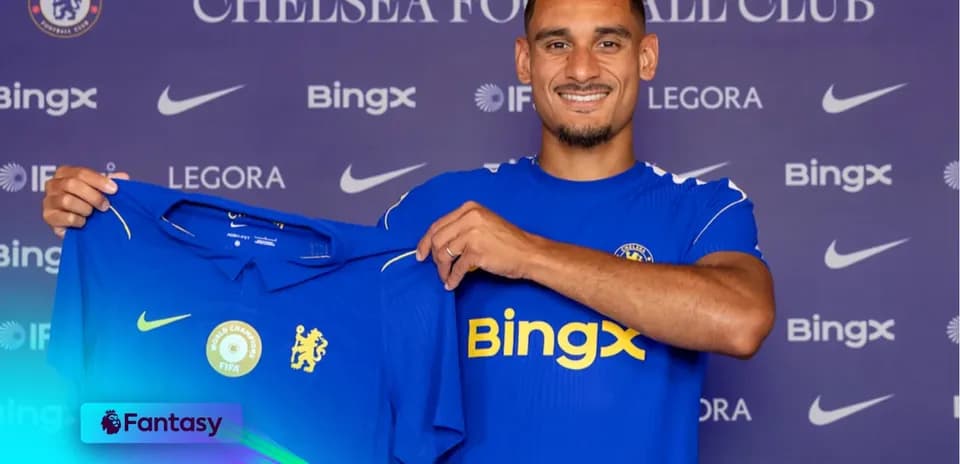 Futbolchi Chelsea formasini ushlab turib, tabassum qilmoqda
