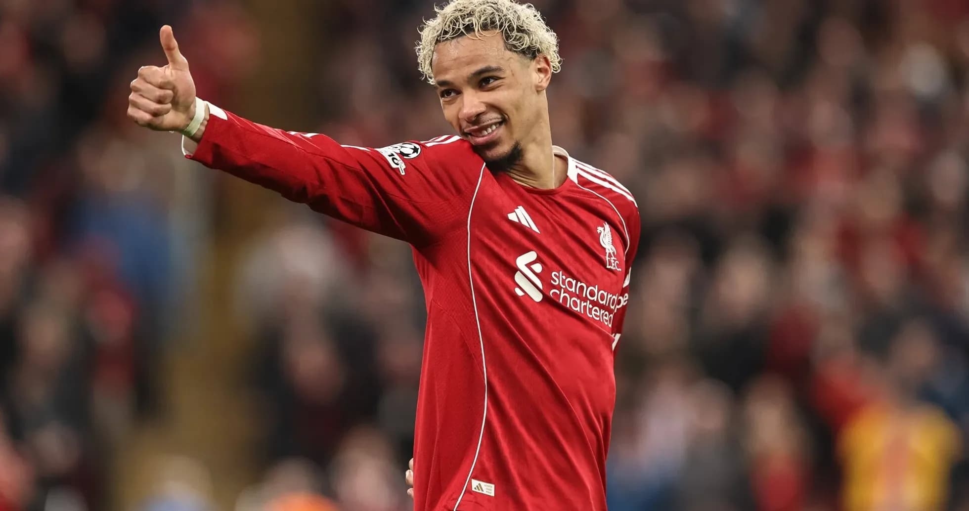Futbolchi Liverpool formasida maydonda qo'lni ko'taradi