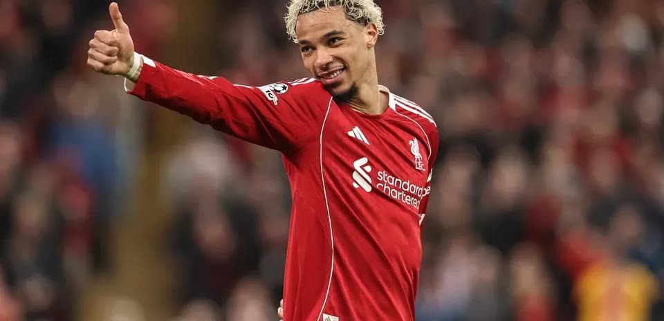Futbolchi Liverpool formasida maydonda qo'lni ko'taradi