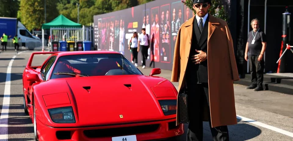 Lewis Hamilton posing next to a red Ferrari