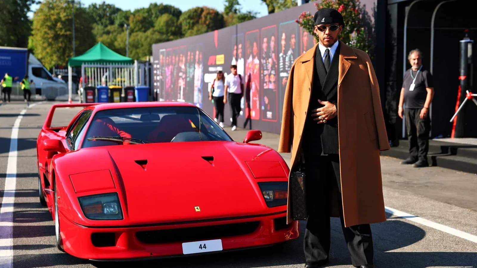 Lewis Hamilton posing next to a red Ferrari