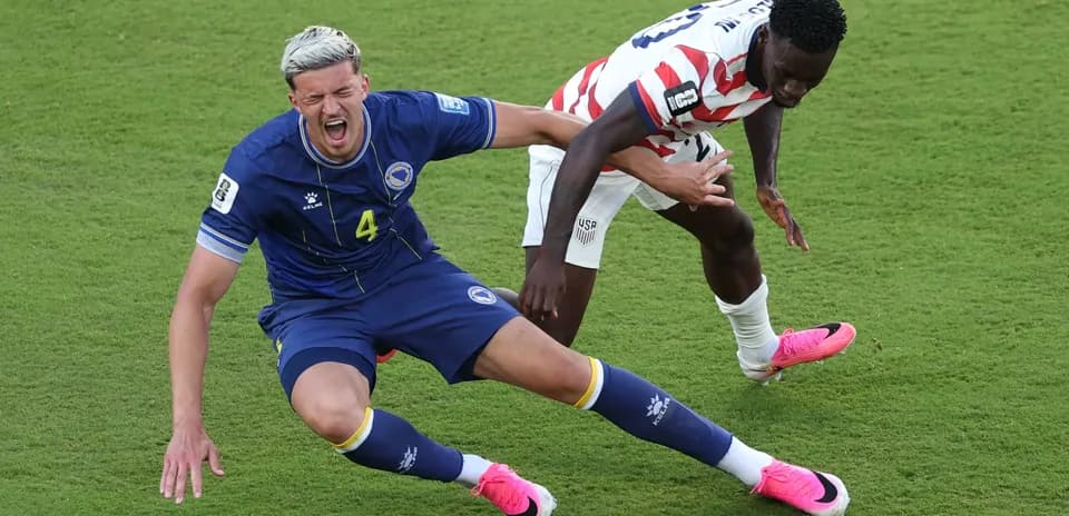 Bosnia player falls while contesting for the ball