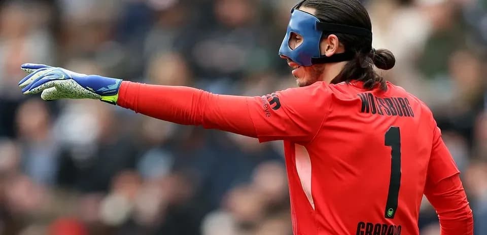 Goalkeeper in red kit signaling during match