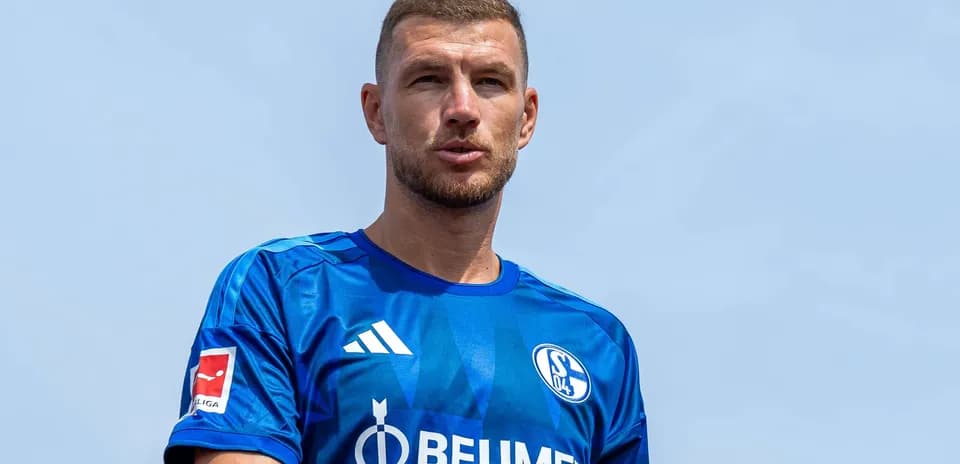Futbolchi ko'k forma kiygan, kameraga qarab turibdi