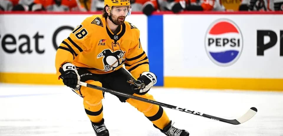 Hockey player skating with puck on ice rink