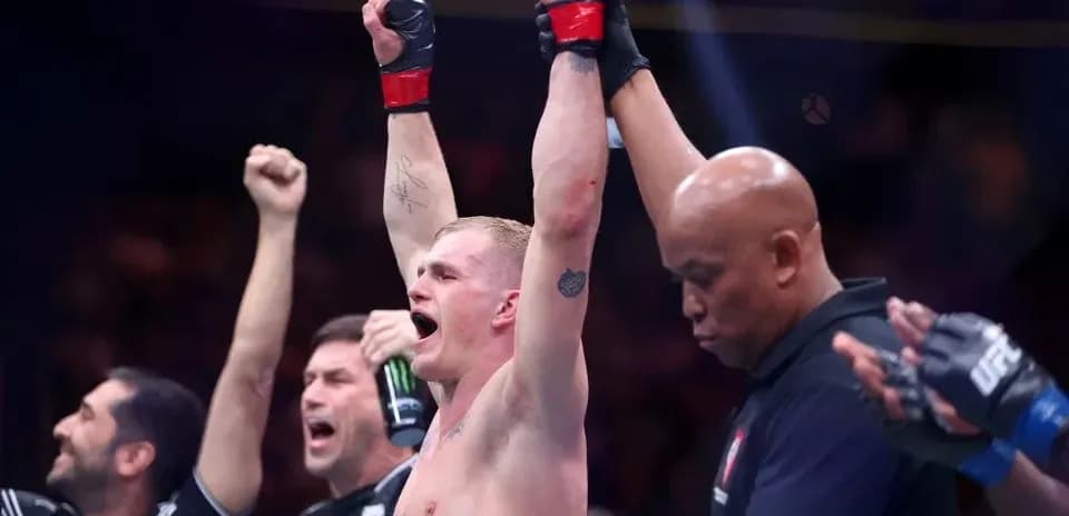 Fighter celebrating victory with raised arms in octagon