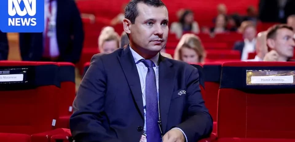 Man seated in conference hall, audience in background