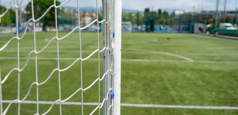 Football goalpost with net on green pitch
