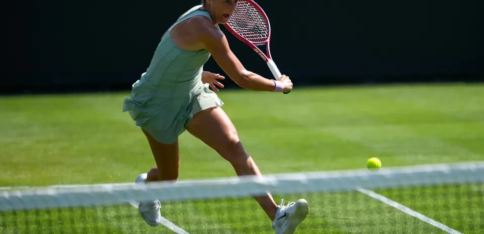 Tennis player reaching for a low ball on court