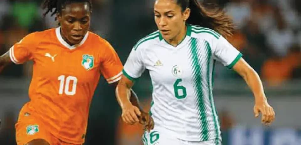 Two female football players competing for the ball