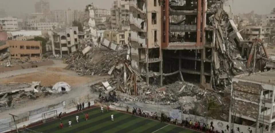 Football match occurring near destroyed buildings