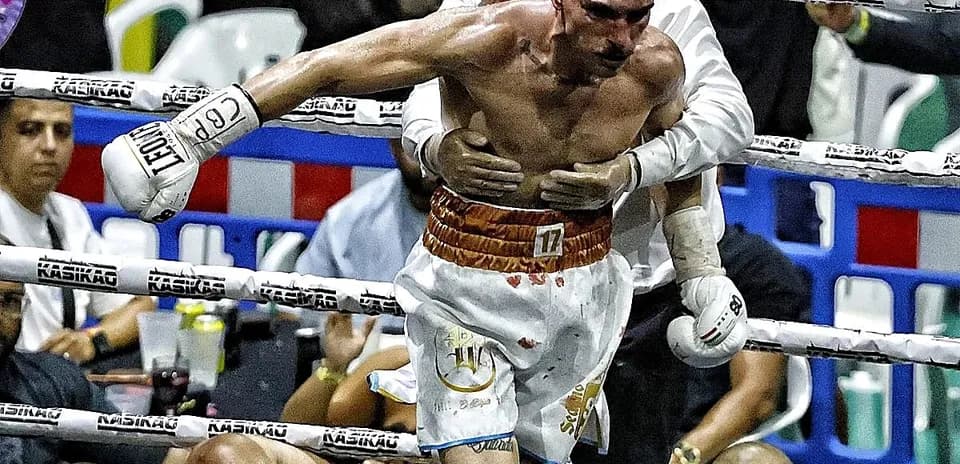 Boxer being helped after a match, opponent on canvas