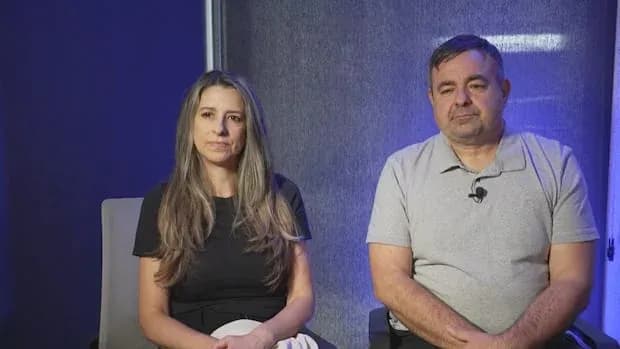 Two people seated in front of a backdrop