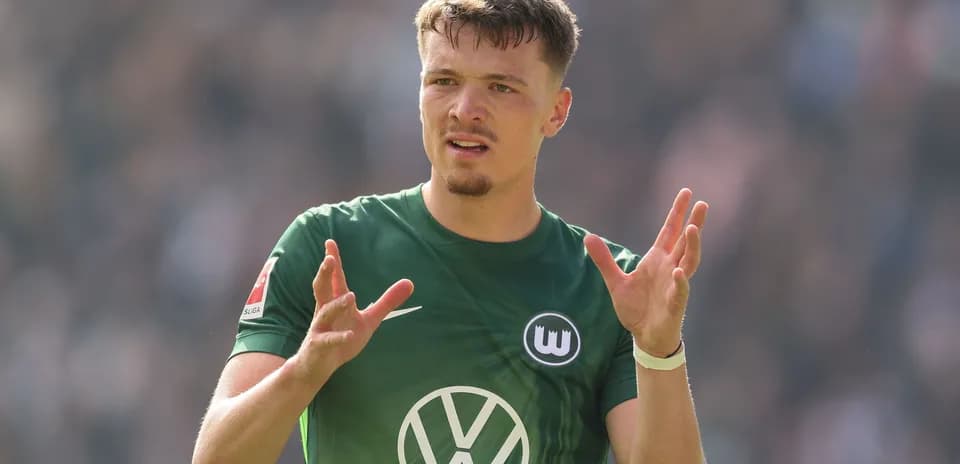 Futbolchi maydonda qo'llarini ko'tarib gapiryapti