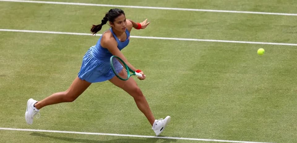 Tennis player reaching for a flying ball on court