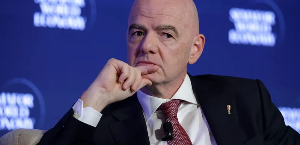 Man speaking at a conference with a thoughtful expression