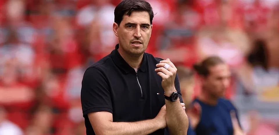 Coach observing match with arms crossed on sidelines