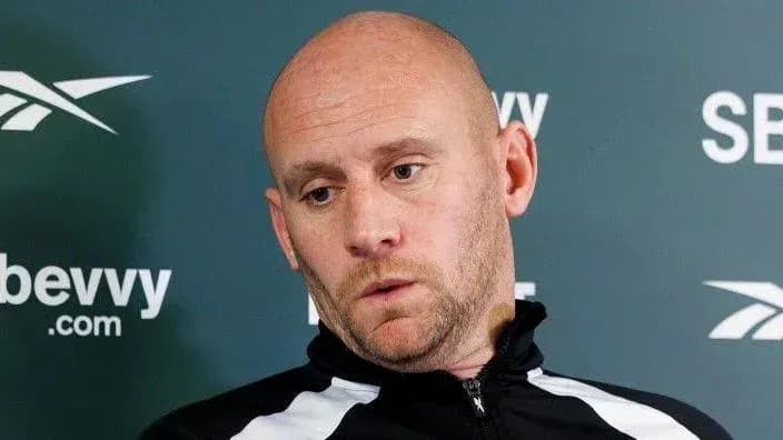 Bald man in tracksuit during press conference