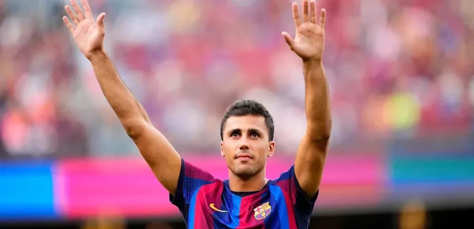 Futbolchi Barcelona formasini kiygan o'yinchi qo'lini ko'tarib turibdi