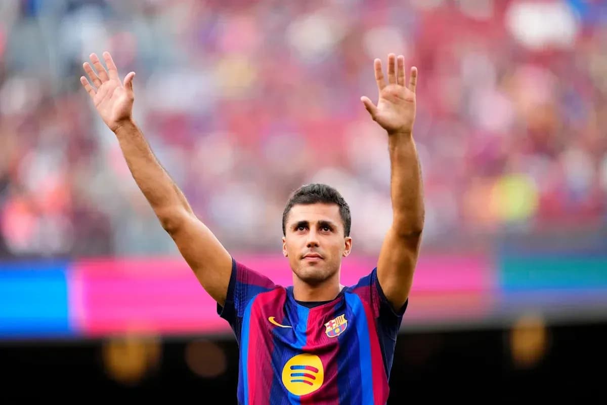 Futbolchi Barcelona formasini kiygan o'yinchi qo'lini ko'tarib turibdi