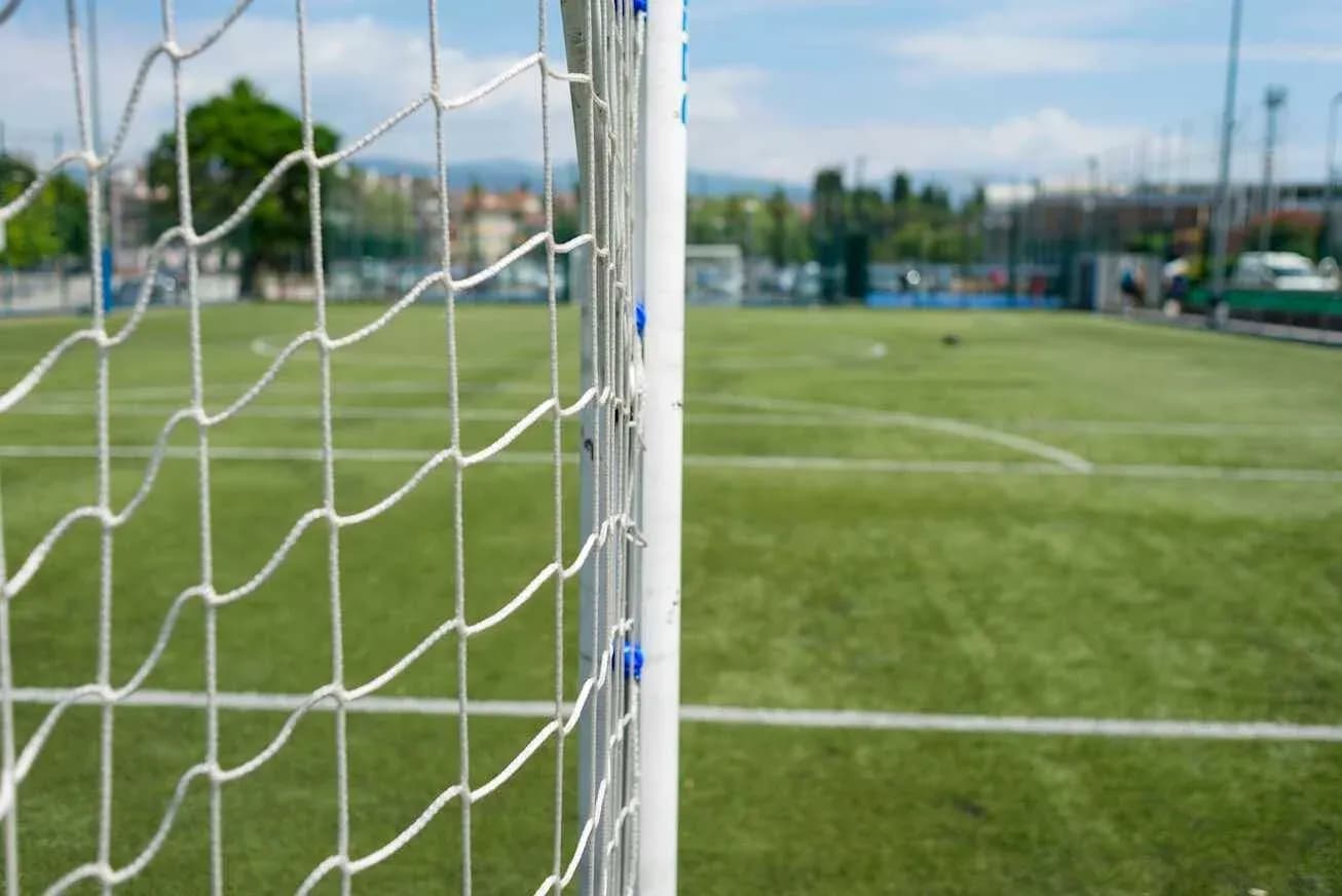 Football goal net with green pitch in background