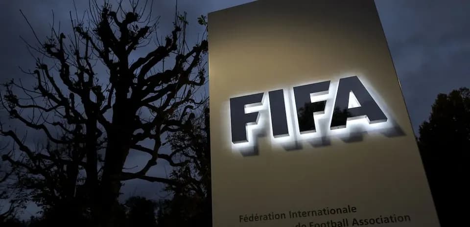 FIFA sign illuminated at dusk with trees