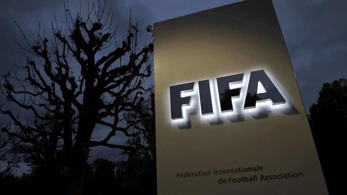FIFA sign illuminated at dusk with trees