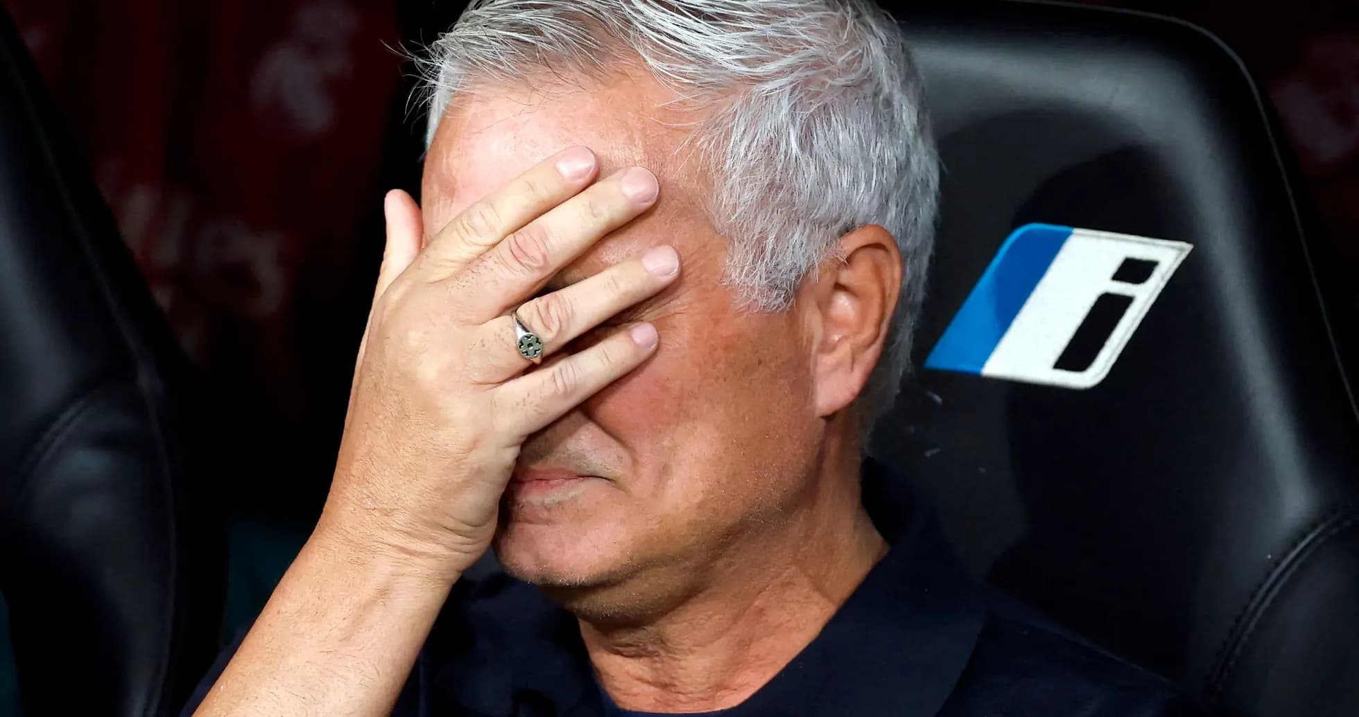 Manager covering face with hand on bench
