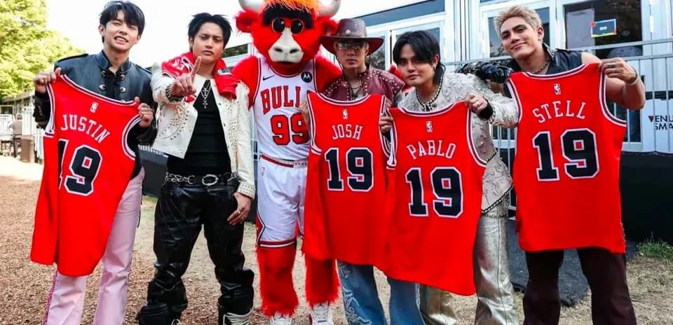 Group holding basketball jerseys with mascot in background