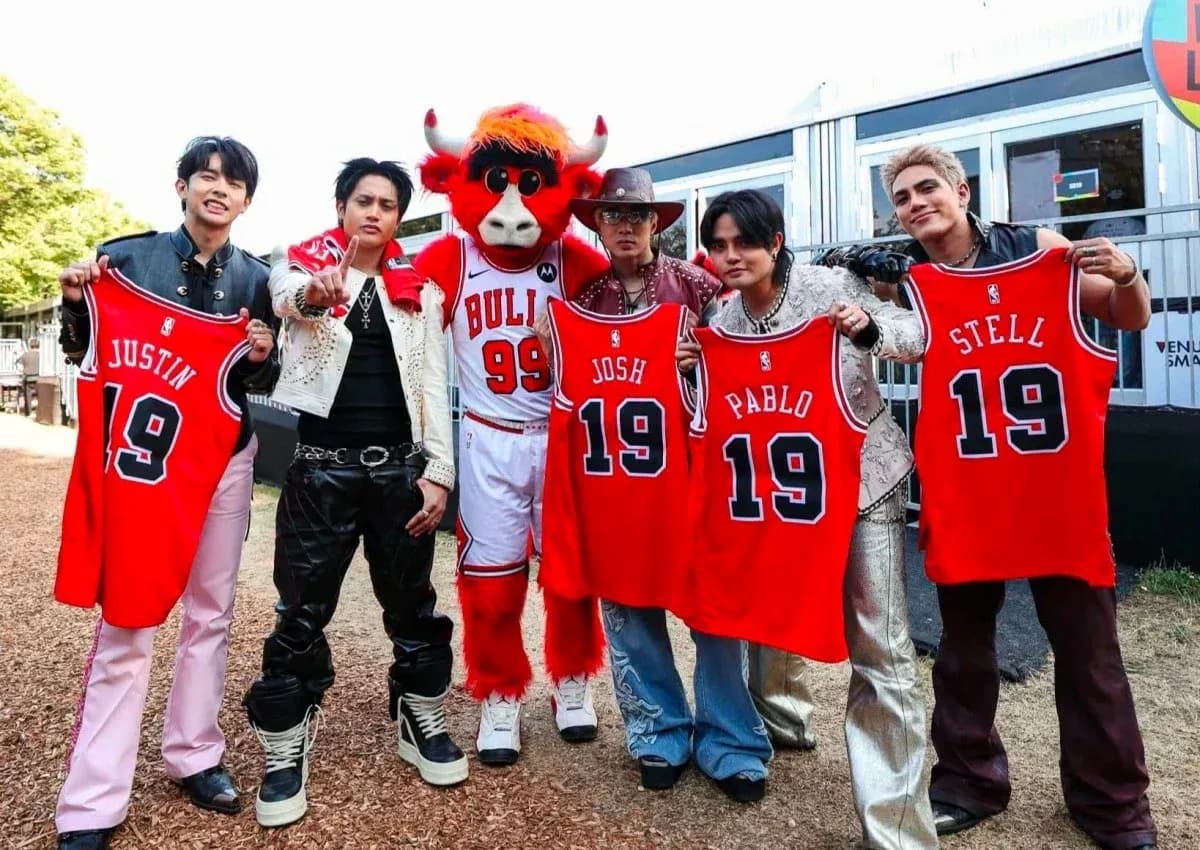 Group holding basketball jerseys with mascot in background