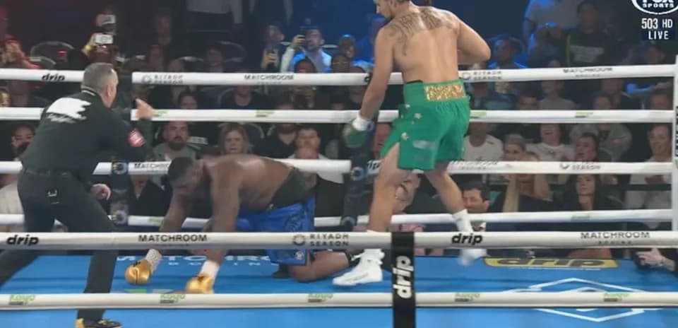 Boxer in green celebrating as opponent kneels down